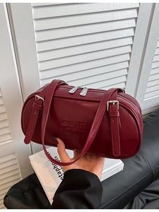 Deep red leather cylinder shoulder bag with adjustable strap and embossed lettering