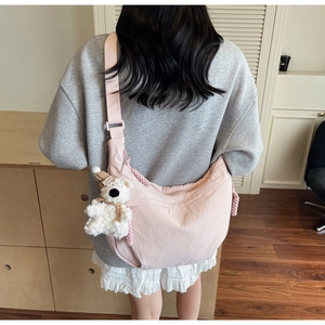 Detail of pink crossbody crescent bag with adjustable strap and plush bear pendant