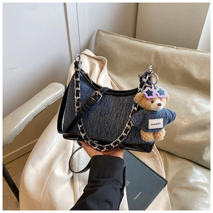 Λεπτομέρεια τσάντας denim με κρεμαστό αρκουδάκι και μαύρο δερμάτινο λουράκι ώμου