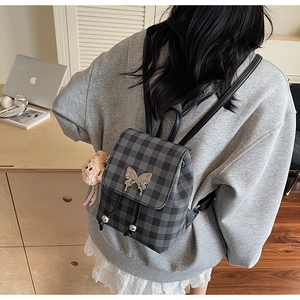Détail d'un sac à dos à carreaux avec fermoir papillon argenté et cordon de serrage