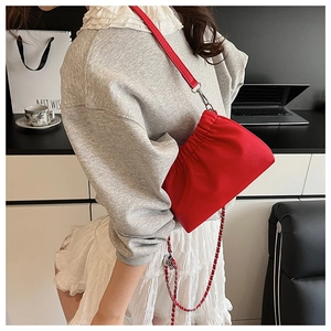 Detail of red lychee leather pleated cloud bag with silver chain and leather strap