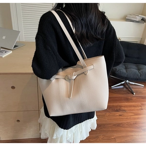 Chic beige leather tote bag featuring buckle detail shown in a modern office setting