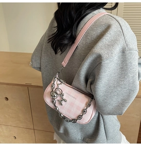 Detail of pink plaid shoulder bag with silver chunky chain and balloon dog charm