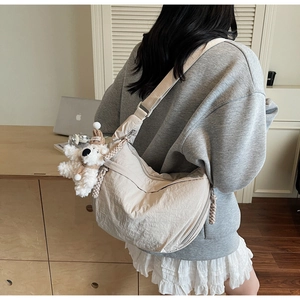 Detail of cream crescent crossbody bag with adjustable strap and cute plush bear charm