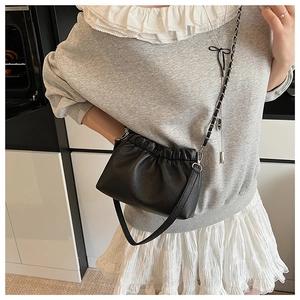 Detailed shot of a black pleated crossbody bag with premium lychee grain texture