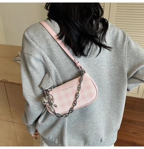 Pink and white checkerboard crossbody bag featuring thick silver chain and metal ball charm