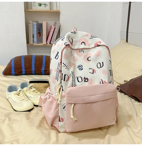 Dettaglio di uno zaino scolastico beige e rosa con motivi a cuore su un letto