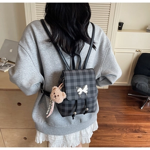 Détail d'un mini sac à dos à carreaux avec papillon argenté et porte-clé ours en peluche
