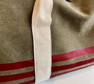 Detail of military green canvas travel bag with white handles and red stripe accents