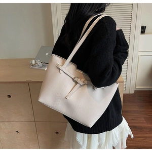Detail of the cream leather tote bag featuring a textured lychee grain and side buckle