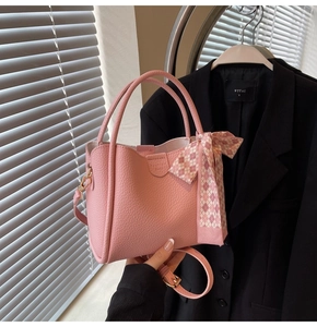 Pink lychee grain bucket bag featuring a decorative checkerboard silk scarf and gold hardware