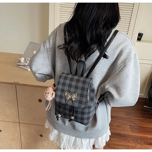 Mannequin portant un mini sac à dos à carreaux avec boucle papillon et breloque ours