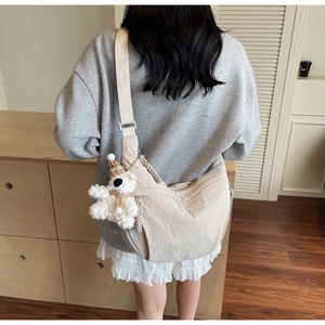 Detail of beige nylon dumpling bag with adjustable strap and cute plush bear charm
