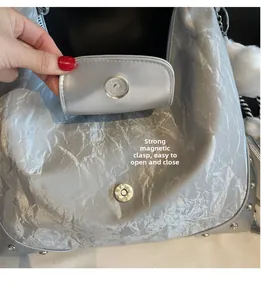 Detail des starken Magnetverschlusses an silberner Faltenhandtasche zum einfachen Öffnen