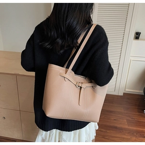 Detail of camel leather tote bag showing fine stitching and round metal buckle on the side