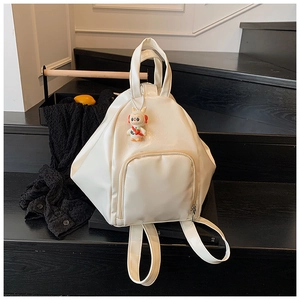 Detail of off-white PU leather backpack with cute rabbit charm on a wooden background