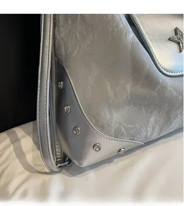 Detail der silbernen Kunstledertasche mit Metallstern-Anhänger und glattem Schultergurt