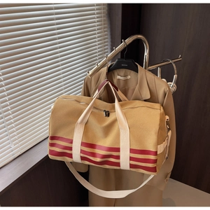Macro detail of large khaki canvas travel bag with red stripes on a vintage coat rack