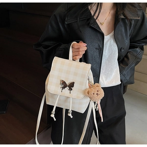 Détail du mini sac à dos à carreaux avec breloque papillon argentée et pendentif ours