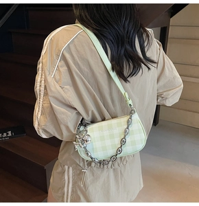 Detail of light green checkered shoulder bag with silver chain and cute rabbit charm