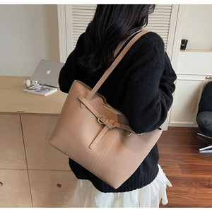 Close-up of khaki tote bag featuring premium lychee grain leather and decorative strap details