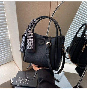 Detail of black pebbled leather bucket bag with a checkered silk scarf on the handle