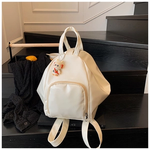 Detailed shot of cream PU leather backpack with zipper pocket and cute rabbit charm