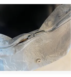 Detail des glatten Metall-Reißverschlusses und der Magnetschnalle einer glänzenden Tasche