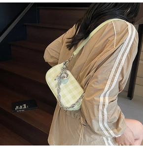 Detail view of light green and yellow checkered bag with silver chain and metal ball charm