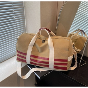 Close-up of khaki canvas travel bag with burgundy stripes and red leather handle wrap