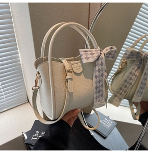Detail of cream crossbody bag with lychee leather texture and lavender silk scarf bow