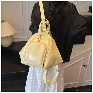 Bright yellow glossy backpack with cute dog charm shown on a female model's back