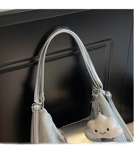 Detail der silbernen Metallic-Tasche mit Doppelgriffen und süßem Plüsch-Wolkenanhänger