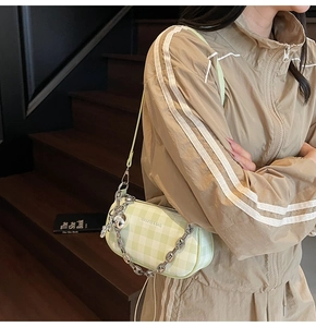 Detail of light green plaid shoulder bag with silver chain strap and charm ball