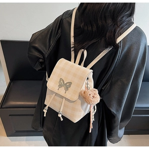 Détail du mini sac à dos à carreaux avec logo papillon en métal et breloque ours en peluche
