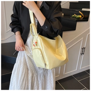 Detail of bright yellow glossy tote bag featuring a functional side pocket and cute bunny charm