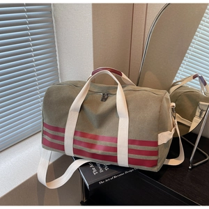 Detailed view of the olive canvas travel bag with red stripes and adjustable shoulder strap