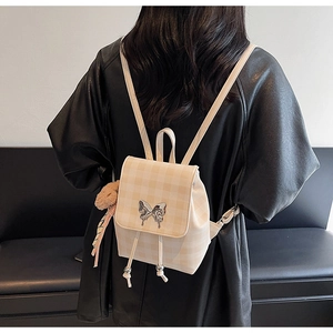 Détail du mini sac à dos à carreaux crème avec boucle papillon et breloque en forme d'ours
