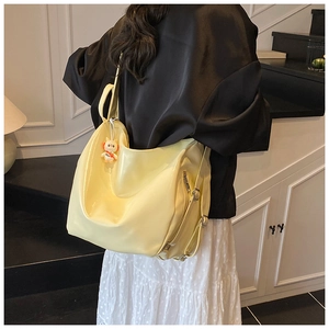 Pale yellow large tote bag with cute white plush bunny charm on a wide shoulder strap