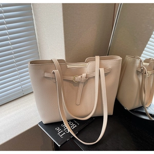 Detail of beige pebbled leather tote bag showing gold hardware and texture
