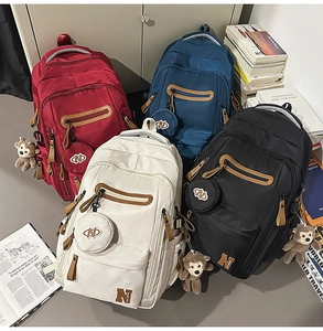 Collection of casual nylon backpacks in four colors with monkey charms and small coin pouches