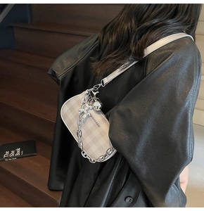 Detail of plaid shoulder bag with chunky silver chain and zip on model's shoulder