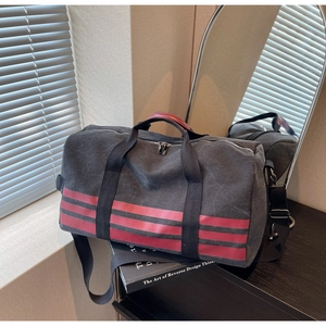 Detail of grey canvas travel bag with red stripes and reinforced leather handles