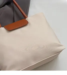 Detailed close-up of cream high-density fabric and brown leather handle on a tote bag