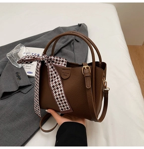 Detailed view of brown lychee-grain bucket bag with silk scarf and logo embossing