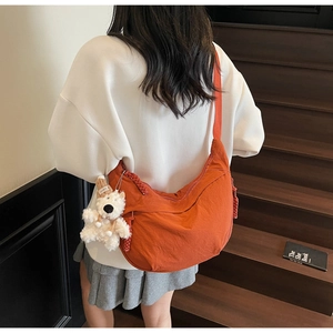 Detail of rust red crescent crossbody bag featuring durable nylon fabric and cute bear charm