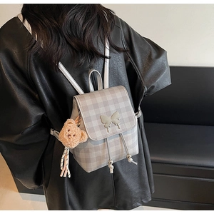 Détail du mini sac à dos à carreaux avec papillon en métal et breloque ours en peluche