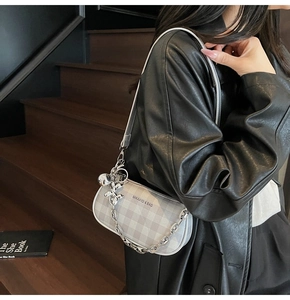 Close-up of checkered baguette bag with silver chain and metal balloon dog charm