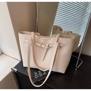 Detail of off-white lychee grain leather tote bag with metal rings and double shoulder straps