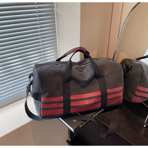 Detail of gray canvas travel bag with red stripes and sturdy adjustable shoulder strap